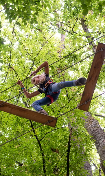 Jeune participant encadré sur passerelle aérienne avec ligne de vie continue