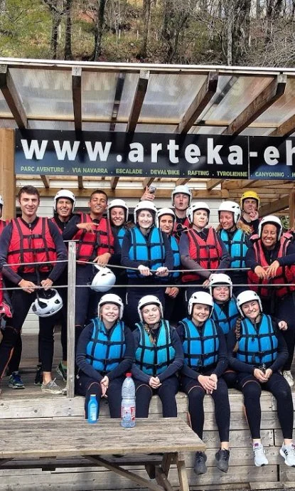 groupe de jeunes adultes avant une descente de rafting, équipés en combinaisons néoprènes, gilets et casques homologués